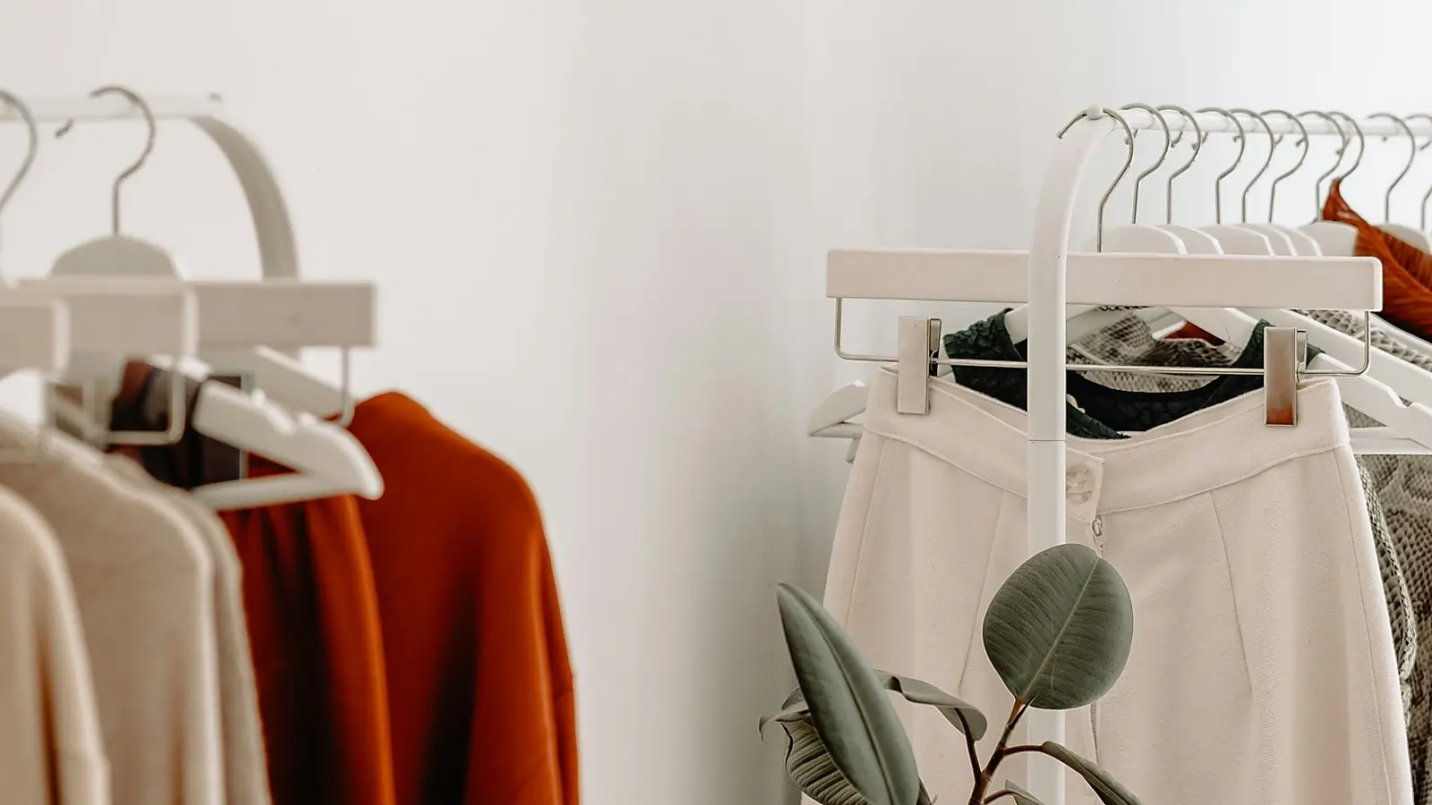Bright minimalist fashion studio with neutral clothing on white racks and a clean eco-inspired styling aesthetic.
