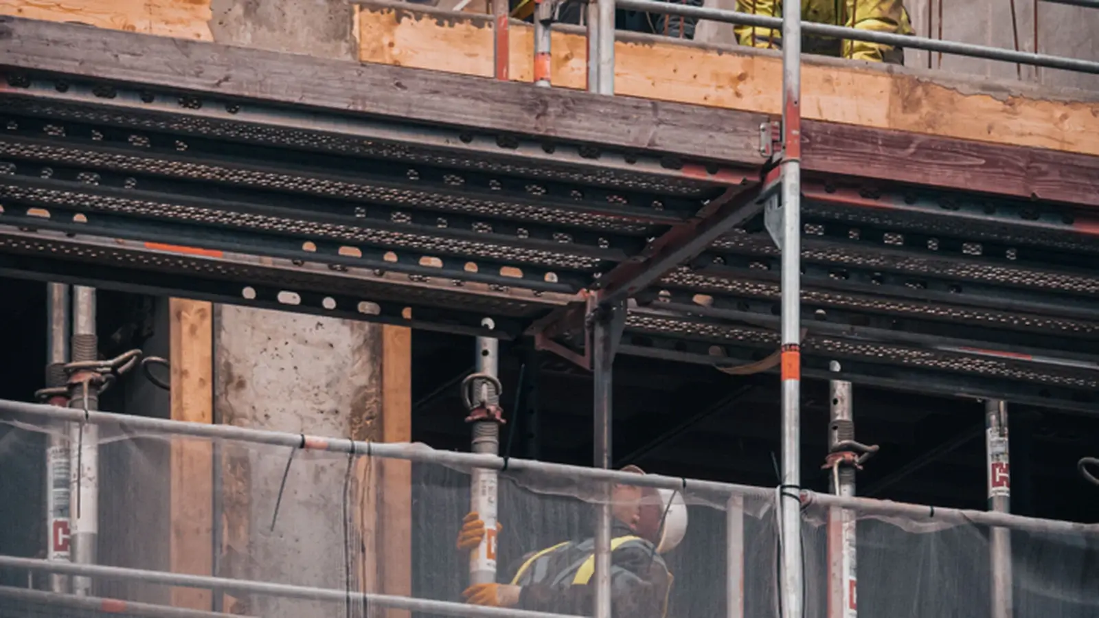 Construction workers on a scaffold at a building site, representing construction and trades services.
