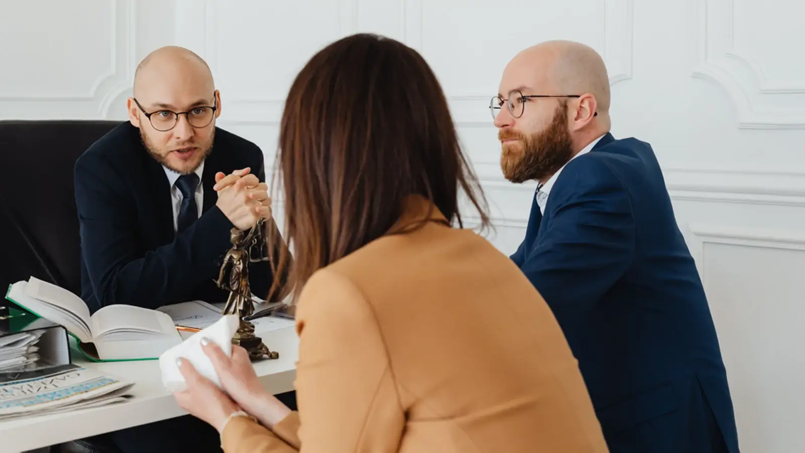 Lawyers meeting with a client in a professional office to discuss legal and financial matters.